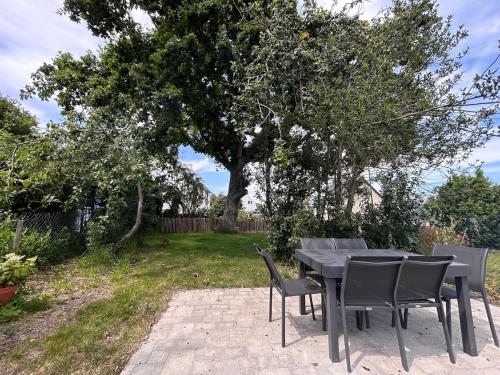 a table and chairs on a patio under a tree at Au gré des marées - proche mer in Plérin