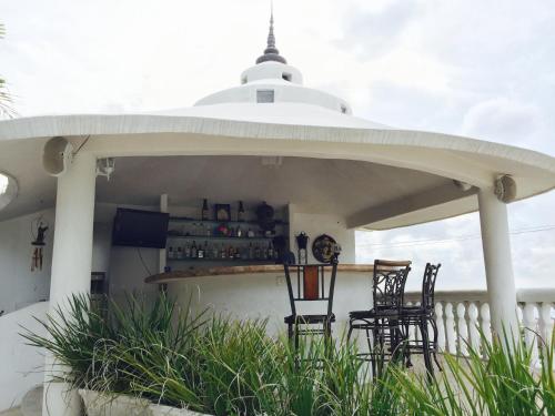 a patio with two chairs and a bar at Villa Costa Chica Comodisimo piscina gigante jardines in Acapulco