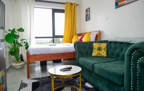 un salon avec un canapé vert et un lit dans l'établissement Stay With Moraa, à Ongata Rongai 