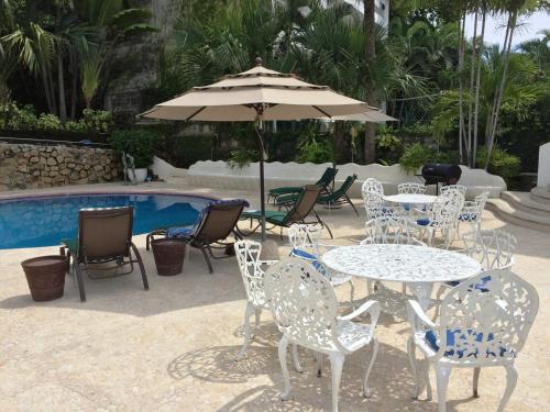 a table and chairs with an umbrella next to a pool at Villa Costa Chica Comodisimo piscina gigante jardines in Acapulco