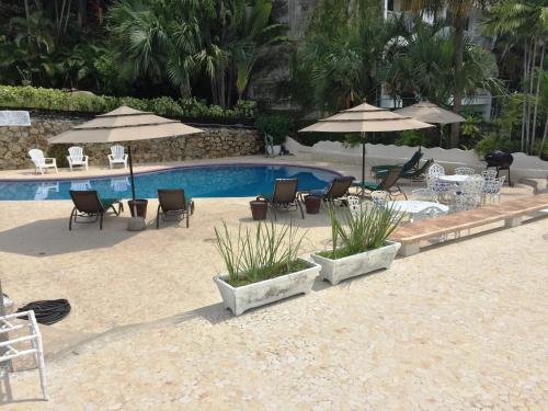 a pool with chairs and tables and umbrellas at Villa Costa Chica Comodisimo piscina gigante jardines in Acapulco