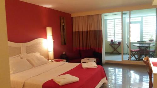 um quarto com uma cama grande e uma parede vermelha em Résidence de la Vielle Tour - Studio particulier vue mer em Le Gosier