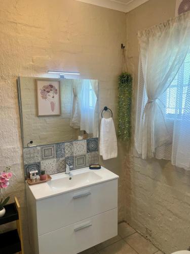 a bathroom with a white sink and a mirror at 42 On Fraser in Howick