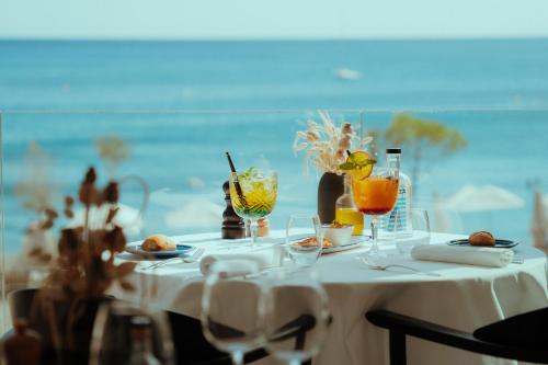 a table with a white table cloth and drinks on it at Les Elmes - Hôtel & Spa in Banyuls-sur-Mer