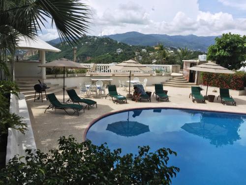 a swimming pool with chairs and tables and umbrellas at Villa Guitarron gran terraza vista espectacular 6 huespedes piscina gigante in Acapulco