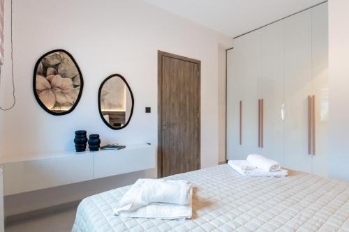 a white bedroom with a bed and a mirror at Lumera Urban Stay - New 2BR Home with Private Parking near Old Town in Chania