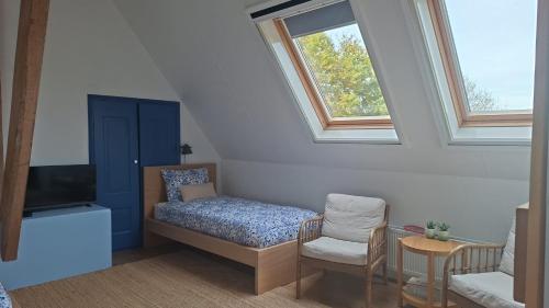 a room with a bed and a chair and a window at B&B Wijdzicht in Wolsum