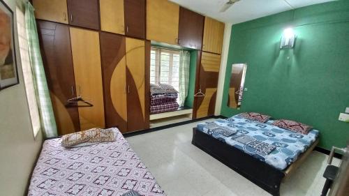 two beds in a room with green walls at The Nest - Garwa in Miraj