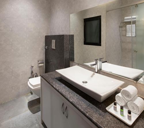 Un baño con lavabo, inodoro y espejo. en Clarks Collection Maanya, en Bareilly