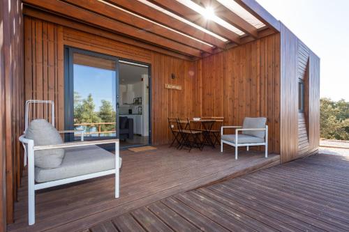 a wooden deck with a chair and a table at Monte Clérigo Casas de Campo in Almodôvar