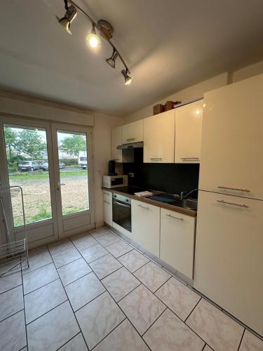 a kitchen with white cabinets and a tile floor at Appartement 2 chambres au coeur de St Cyr avec parking privé in Saint-Cyr-sur-Loire