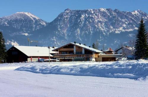 a house in the snow with mountains in the background at Hoamatl in Tannheim