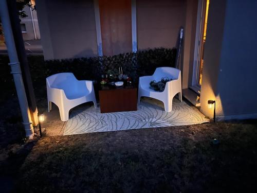two white chairs sitting on a patio at night at Appartement convivial à Équemauville de 36 m² avec jardin in Équemauville