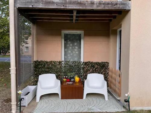 two white chairs sitting on the porch of a house at Appartement convivial à Équemauville de 36 m² avec jardin in Équemauville