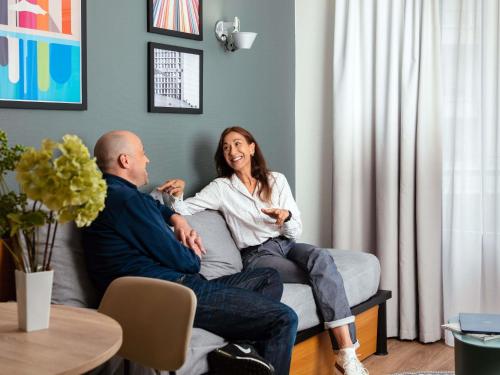 a man and a woman sitting on a couch at Aparthotel Adagio La Défense Le Parc in Courbevoie
