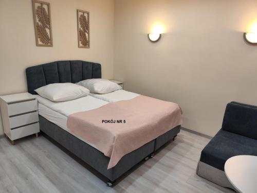 a small bedroom with a bed and a chair at Willa Maja in Ciechocinek