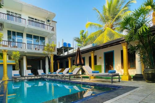 einem Pool vor einem Haus mit Stühlen und einem Gebäude in der Unterkunft Eros Green House in Unawatuna