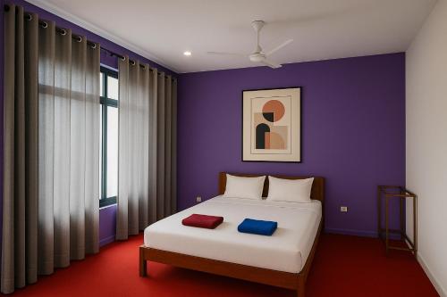 乌纳瓦图纳Eros Green House的一间卧室配有一张紫色墙壁的床