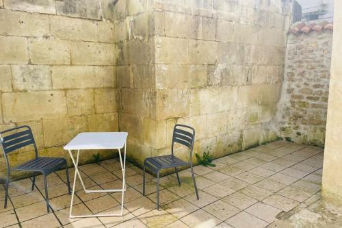 a table and chairs sitting next to a wall at Bel appartement avec cour privée in Saint-Jean-dʼAngély