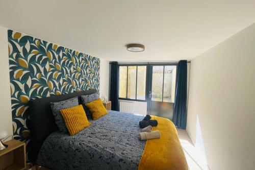 a bedroom with a bed with yellow pillows and a window at Bel appartement avec cour privée in Saint-Jean-dʼAngély