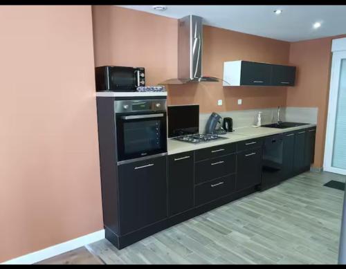 a kitchen with black cabinets and a stove top oven at Villa Notre-Dame in Boulogne-sur-Mer