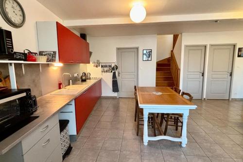 une cuisine avec des placards rouges et une table en bois dans l'établissement Le Faubourg, à Saint-Jean-dʼAngély