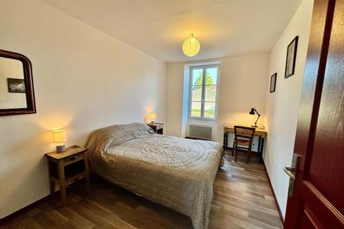 une chambre avec un lit et deux tables et une fenêtre dans l'établissement Le Faubourg, à Saint-Jean-dʼAngély