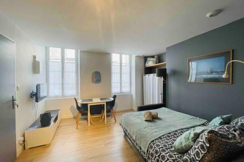ein Schlafzimmer mit einem Bett, einem Schreibtisch und einem Tisch in der Unterkunft Studio moderne rénové in Saint-Jean-dʼAngély