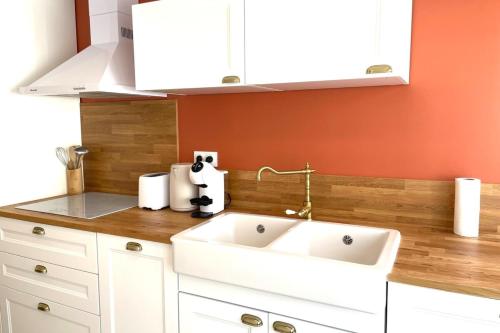 cocina con fregadero blanco y pared de color naranja en La Touzetterie avec SPA-cour privée, en Saint-Jean-dʼAngély