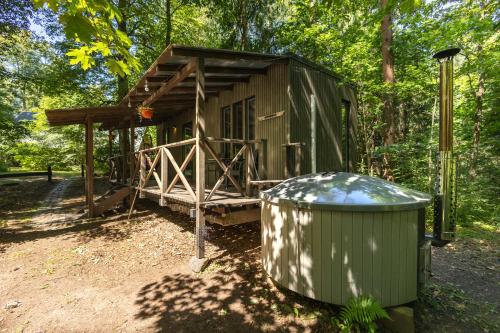 una pequeña choza con un cubo de basura al lado en Meža māja, en Zaķumuiža