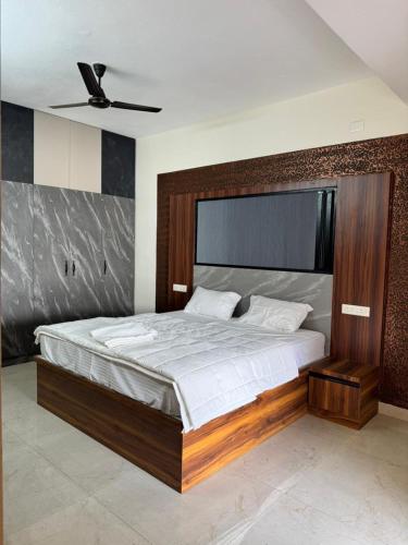 a bedroom with a large bed with a wooden headboard at Marvee Luxus Stay in Coimbatore