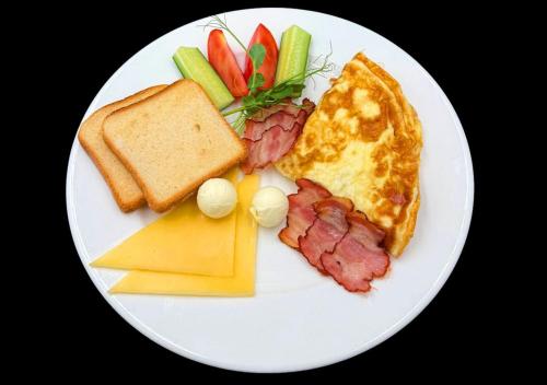 a plate of breakfast food with eggs bacon cheese and vegetables at Гостиница Siesta Киев in Kyiv