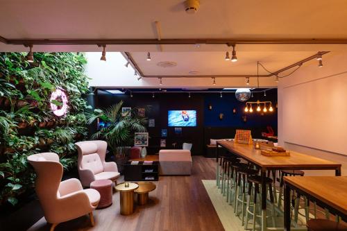 a restaurant with a green wall with tables and chairs at Hotel The Dutch Maastricht in Maastricht