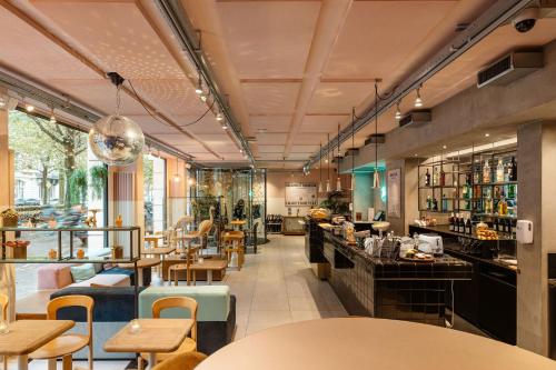 a restaurant with tables and chairs and a bar at Hotel The Dutch Maastricht in Maastricht