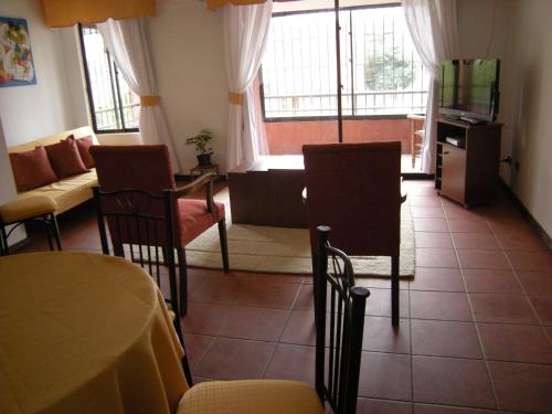 ein Wohnzimmer mit einem Tisch, Stühlen und einem TV in der Unterkunft Apart Hotel Punto Real in Curicó