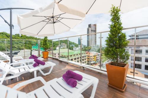 a balcony with white chairs and an umbrella at Hotel Zing in Pattaya South