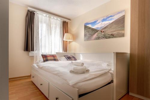 a white bed in a room with a window at Alpenheim Apartment in Andermatt