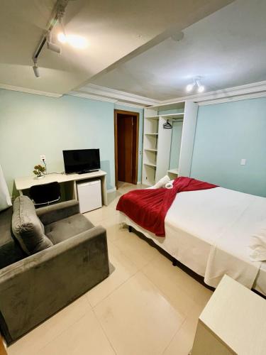 a bedroom with a large bed and a couch at Residencial Morada Coqueiros in Florianópolis