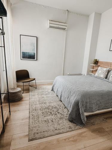 a white bedroom with a bed and a chair at Your home on Smith St Collingwood Melbourne with parking in Melbourne