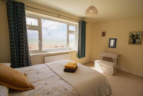 une chambre avec un lit et une fenêtre avec vue sur la plage dans l'établissement Sunset Beach House By Air Premier, à Seaford