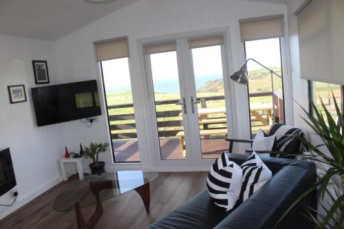 een woonkamer met een bank en een groot raam bij Amazing Sunsets and Sea Views - Lodge Cabin Farm Stay - Caol Ila - Lodge 8 in Stranraer