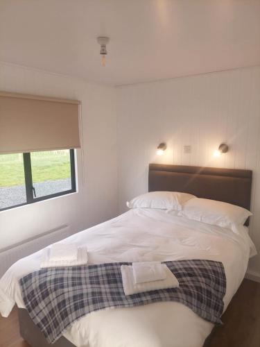 a bedroom with a bed with two towels on it at Amazing Sunsets and Sea Views - Lodge Cabin Farm Stay - Caol Ila - Lodge 8 in Stranraer