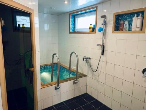 een badkamer met een bad, een douche en een spiegel bij Cozy Garden House with a Sauna in Tallinn