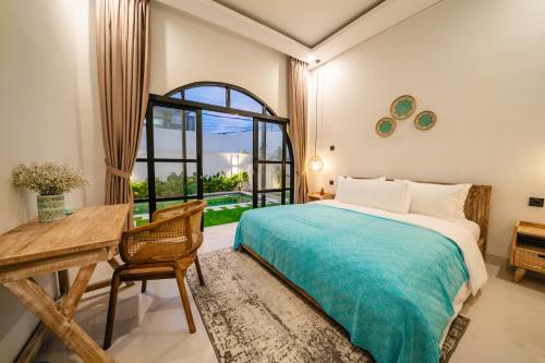 a bedroom with a bed and a desk and a window at Paica House Nusadua in Nusa Dua