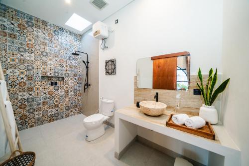 a bathroom with a sink and a toilet and a mirror at Paica House Nusadua in Nusa Dua