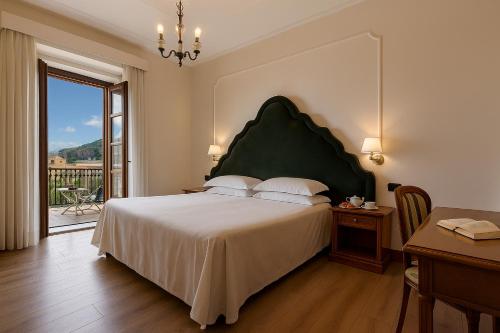 a bedroom with a large bed with a green headboard at Majestic Palace Hotel in Sant'Agnello