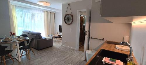 une cuisine et un salon avec une table et une horloge au mur dans l'établissement BALTICUS - Apartamenty Może nad Morze Międzyzdroje, à Międzyzdroje