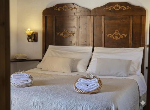 a bed with a wooden headboard and two baskets on it at S'Arrosa de Monti in Villaputzu