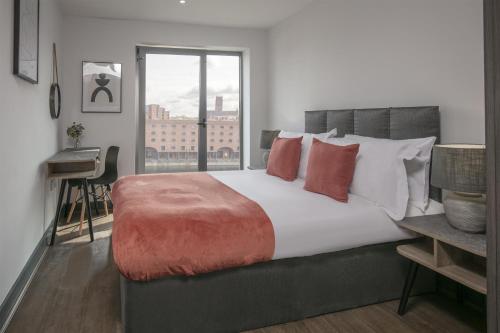 a bedroom with a large bed with red and white pillows at Dockside Aparthotel, Best Western Signature Collection in Liverpool