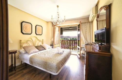 a bedroom with a bed and a television and a balcony at La Elegancia del Centro by Alogest in Zaragoza